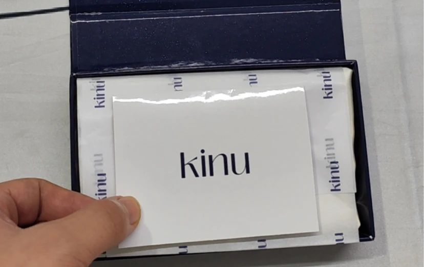 Geöffnete KINU-Geschenkbox mit Seiden-Augenmaske, inklusive Seiden-Haargummis und Markeneinlagen.
