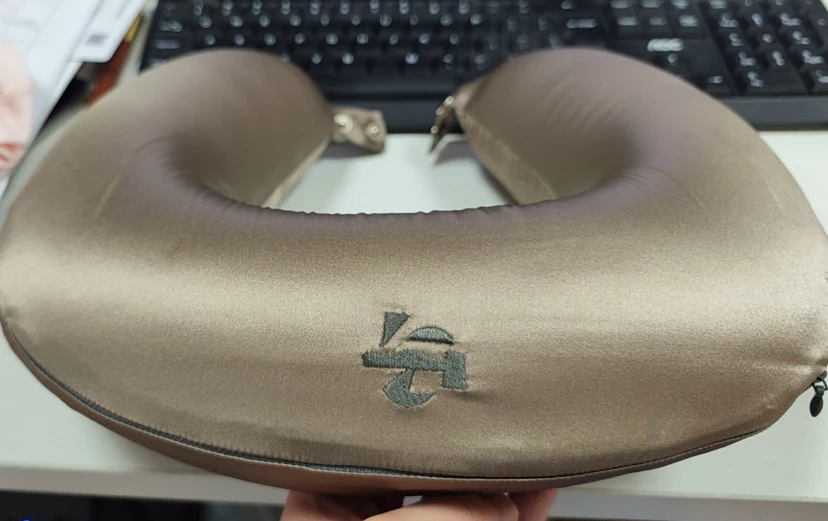 Primer plano de la almohada cervical de seda personalizada con logotipo de la marca y hebilla portátil para viajes de larga distancia.