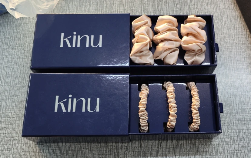 Gestapelte KINU-Geschenksets mit Seiden-Augenmaske, versandfertig.