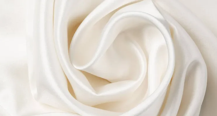 White silk charmeuse fabric close-up showing glossy satin surface