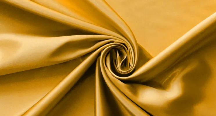 Gold silk charmeuse fabric close-up with warm metallic sheen